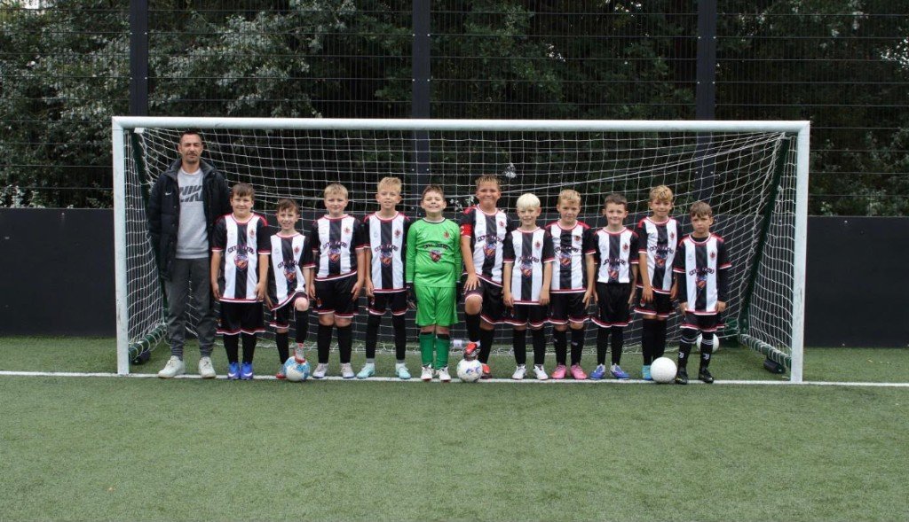 Harwich and Parkeston Blues under 10s lined up with their coach in front of a goal